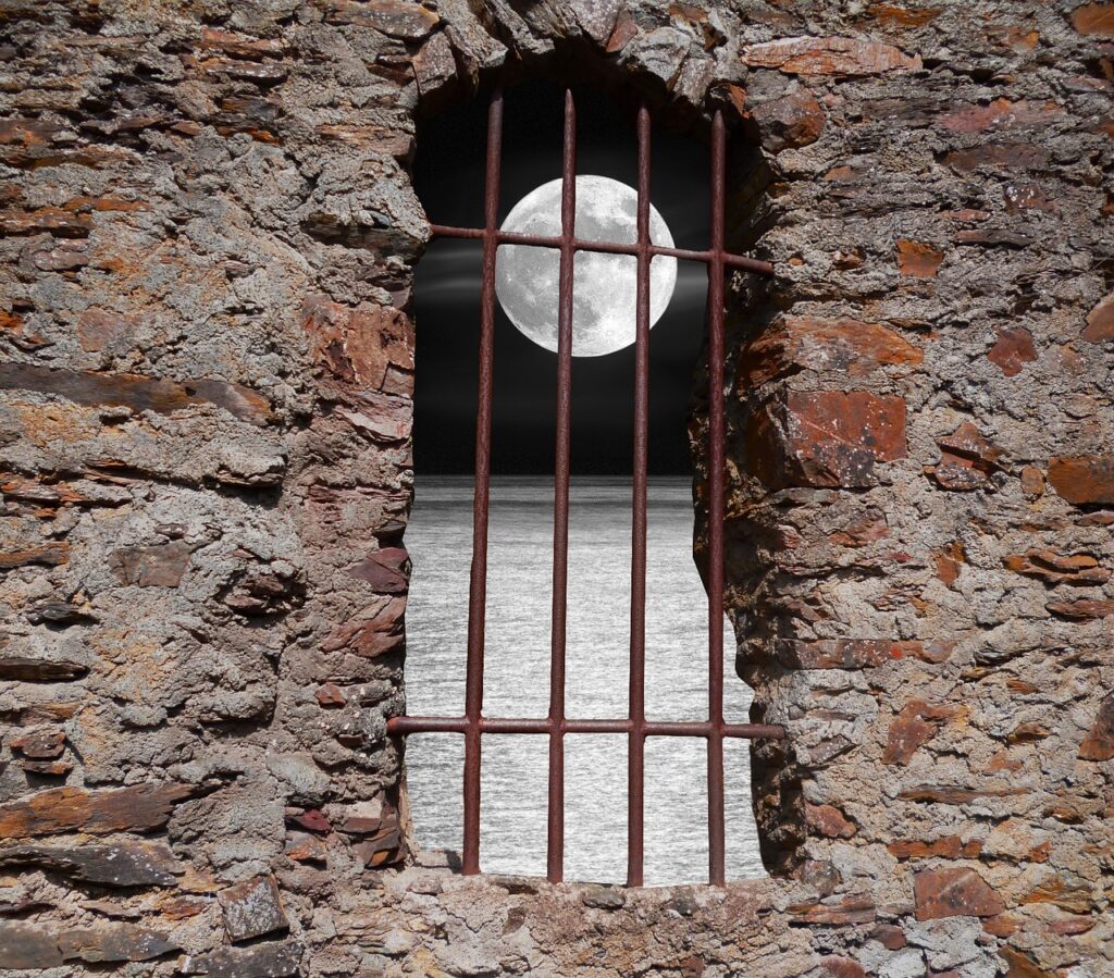 Ventana con barrotes desde donde se ve la luna. La culpa es tuya.